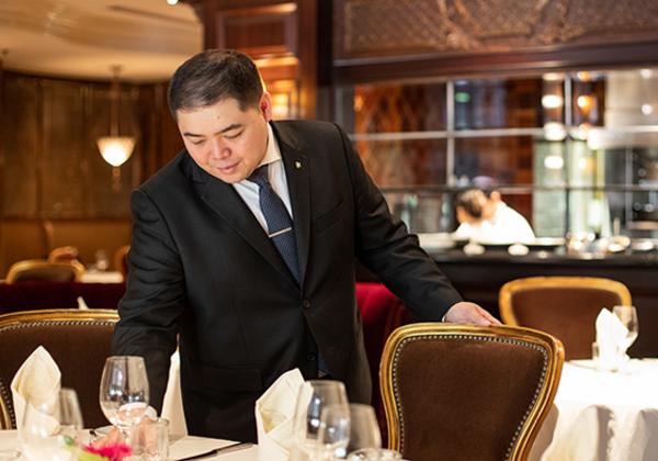 Young man in a suit overlooking a fine-dining table