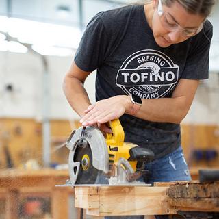 A women using a skill saw in a workshop. 