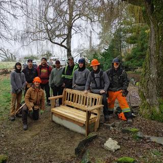 Group of carpentry students around a bench they built.